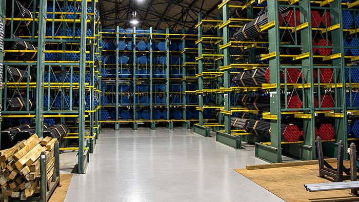 Workers pick and store PVC-coated pipe in a complex cantilever rack system