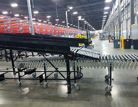 warehouse interior with flexible roller conveyor underneath herringbone transition conveyor