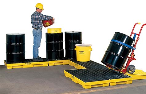 worker pouring hazardous material into a drum sitting on a U-shaped configuration of spill control platforms