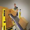 Man standing near stack of boxes and placing boxes on an inclined conveyor