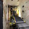 worker inside truck trailer with stack of boxes and conveyor