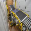 conveyor inside a truck trailer with stack of boxes behind it