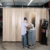 Worker using equipment with acoustic curtain fully extended to deaden noise to adjacent work areas