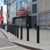 Row of black bollards on a city sidewalk in front of a store
