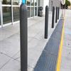 Dark gray bollard sleeves on a sidewalk in front of a store