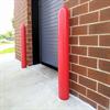 Red bollards flanking a roll-up door on a brick building