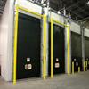 Yellow goal post style guardrails in front of black overhead doors