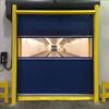 Yellow goal post style guardrail in front of blue overhead door with window to interior chamber