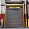 Yellow goal post style guardrail with yellow bar suspended from horizontal beam in front of gray door