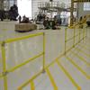 Yellow handrail in hangar with plane, crane, and platform in the background