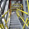 Yellow handrail on industrial stairs with metal grating