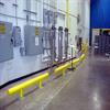 Row of yellow guardrail in front of wall with electrical boxes