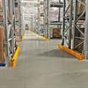 Sections of yellow rail at the feet of pallet rack uprights in a warehouse
