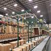 Overhead conveyor delivering empty cartons to a pick line