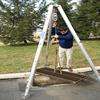 tripod crane lifting a metal grate
