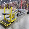 Restuff-it ergonomic conveyor connected to telescopic belt conveyor in warehouse with pallet racks