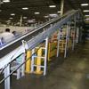 Incline conveyor running to centralized mezzanine. Safety nets are installed to prevent falling items.