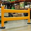 Yellow guardrail in front of a forklift and loaded pallet rack