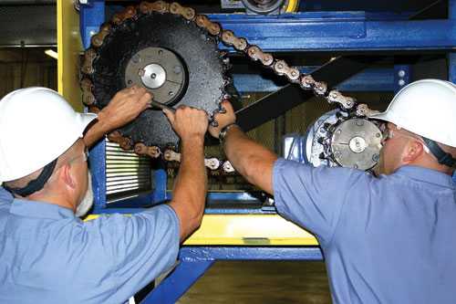two men in hard hats adjusting gears in warehouse equipment