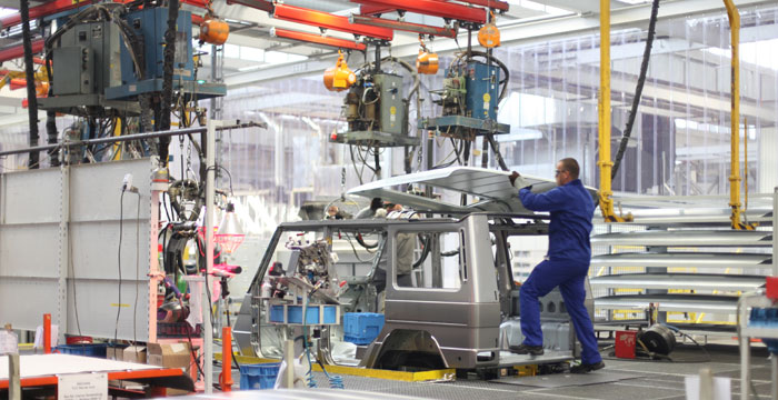 man installing roof in an auto assembly line