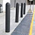 Dark gray bollard sleeves on a sidewalk in front of a store