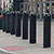 Row of black bollards on a city sidewalk in front of a store