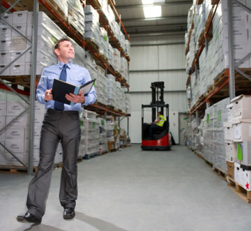 manager in a warehouse forklift area between rack aisles