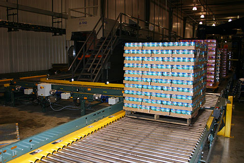 conveyor moving a palletized load of cans and boxes