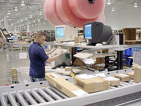 worker at packing station with boxes on conveyor line