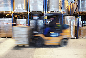 blurred forklift driving past pallet racks