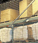 Pallet rack loaded with cartons and bales, protected by netting