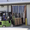 Forklift moving a load through vinyl strip doors