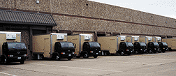 row of GroceryWorks trucks parked at warehouse docks