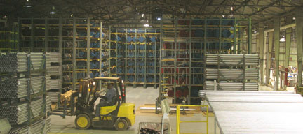 Workers pick and store PVC-coated pipe in a complex cantilever rack system