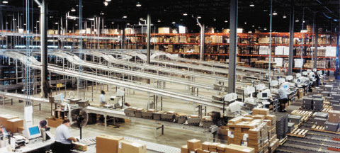 pallet rack and conveyor in a warehouse with workers at computer workstations